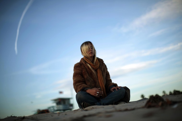 A woman meditates at sunset on Venice Beach in Los Angeles, on New Year's Eve