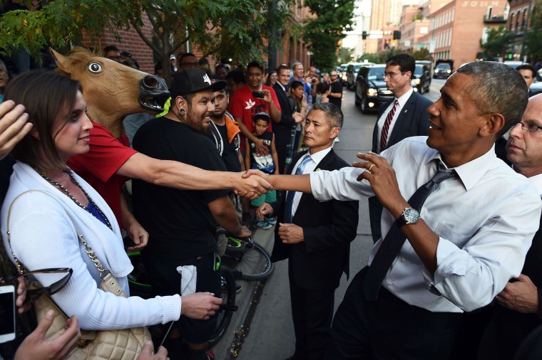 Image: President Barack Obama jokingly reacts as he shakes hands with a man wearing a horse head mask