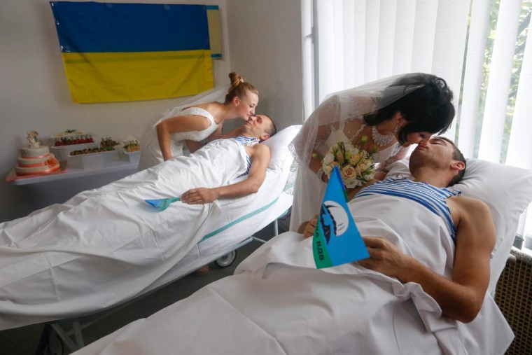 Image: Wounded members of the Ukrainian force kiss their brides in hospital beds