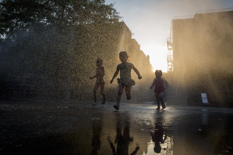 Image: Children play with a sprinkler at a playground in the Park Slope section of the Brooklyn borough of New York