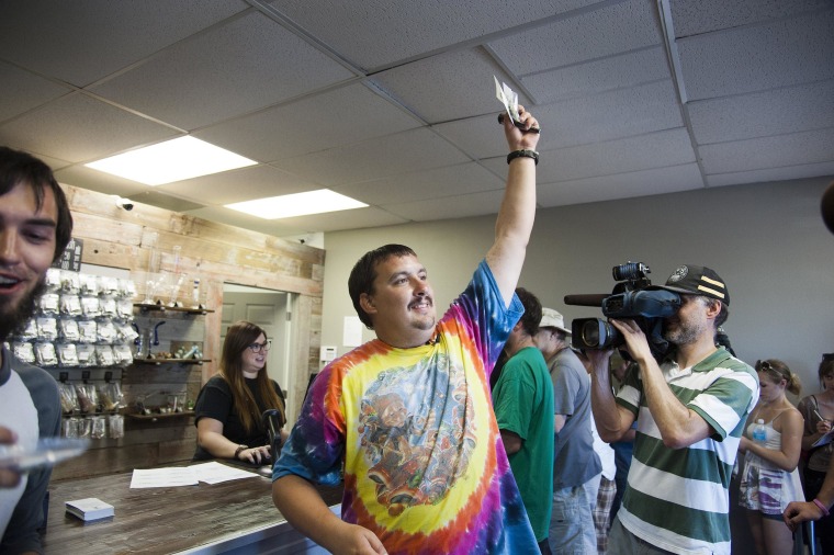 Image: Mike Boyer turns to the crowd outside, showing off the 4 grams of marijuana he bought as the first in line to legally purchase marijuana at Spokane Green Leaf