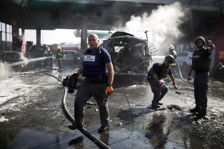Image: Israeli police explosive experts survey the scene at a petrol station after it was hit by a rocket in Ashdod