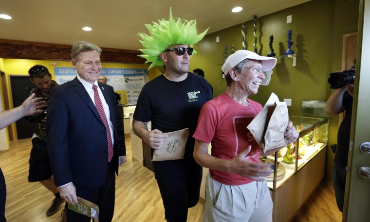 Image: Seattle City Attorney Pete Holmes, left, Jeremy Cooper and Deb Greene walk out after being among the very first customers to legally purchase recreational pot in Seattle at Cannabis City, Tuesday, July 8, 2014. 