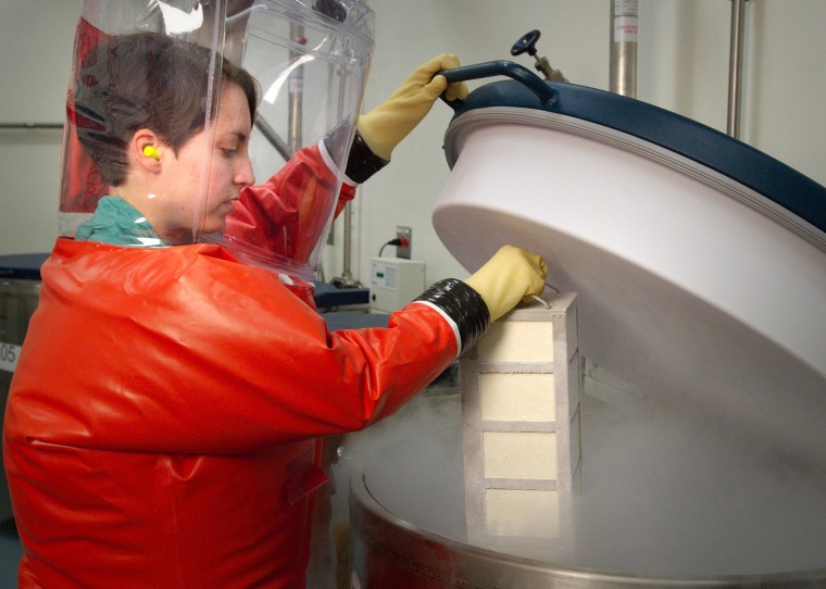 Image: Centers for Disease Control microbiologist and Special Pathogens Branch (SPB) staff member, Dr. Amy Hartman, in the process of inserting a rack of boxes containing biological stocks into a liquid nitrogen freezer where they would be stored in a BSL