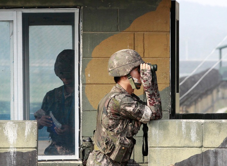 Image: A South Korean army soldier looks through a pair of binoculars at a military check point