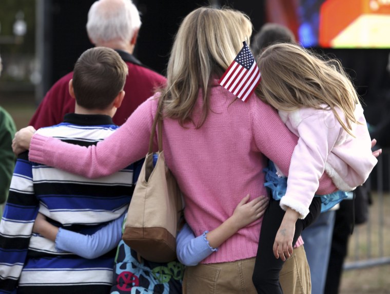 Image: A woman huddles with her children while watching a speech next to the Myrtle Beach Convention Center in Myrtle Beach on Jan. 16, 2012.