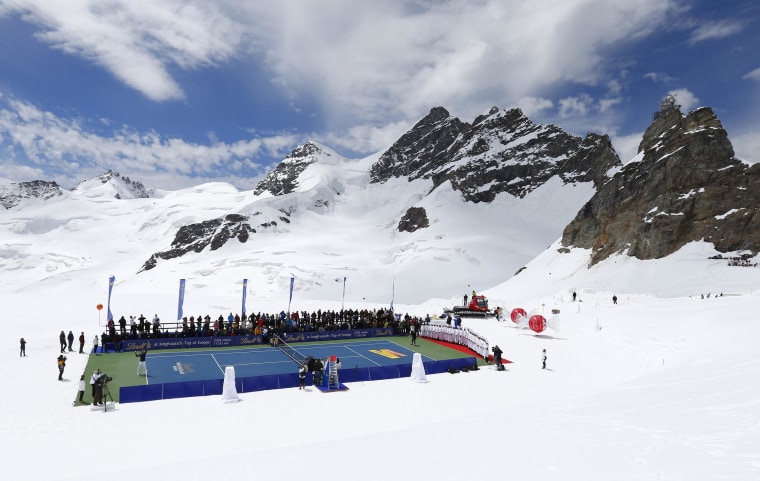 Image: Swiss tennis player Federer serves a ball to U.S. skier Vonn during a promotional tennis event on the Aletsch glacier at the Jungfraujoch
