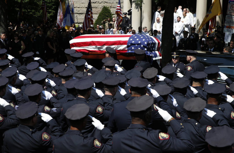 Image: Police officers salute as the casket carrying slain Jersey City police officer Melvin Santiago is carried into St. Aloysius Catholic Church for his funeral service in Jersey City