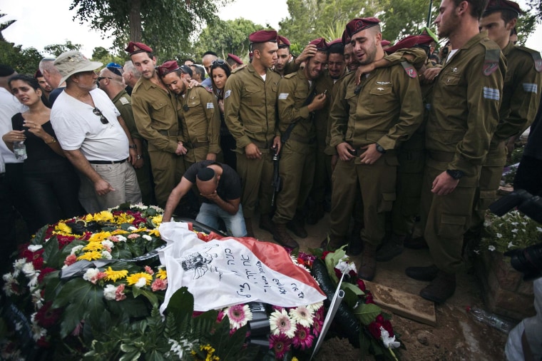 Image: Israeli soldiers mourn with the brother of Israeli soldier Bnaya Rubel during Rubel's funeral in Holon