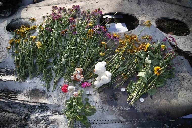 Image: Flowers and mementos left by local residents lie on wreckage at the crash site of Malaysia Airlines Flight MH17, near the settlement of Grabovo in the Donetsk region