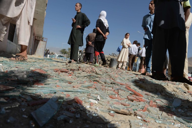 Image: Afghan men look on amid broken glass and debris at the site of a suicide attack in Kabul