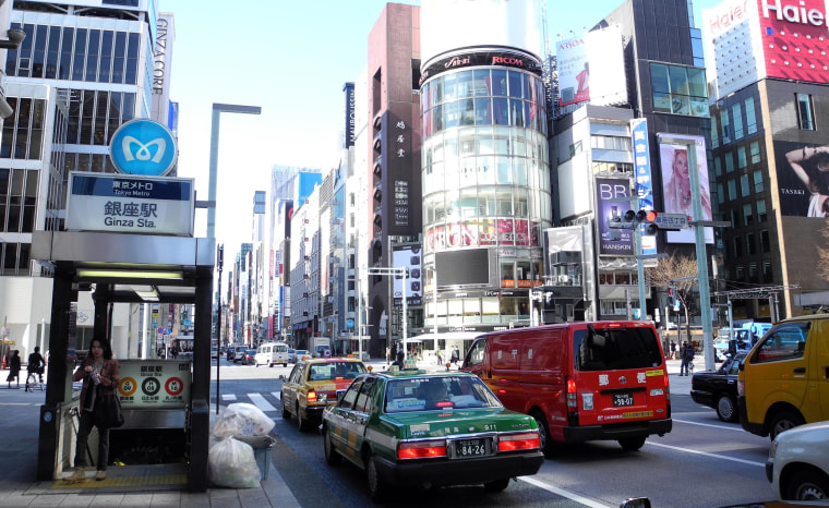 Image: A woman comes out of Ginza metro station as a taxi passes by in downtown Tokyo on March 17, 2011.