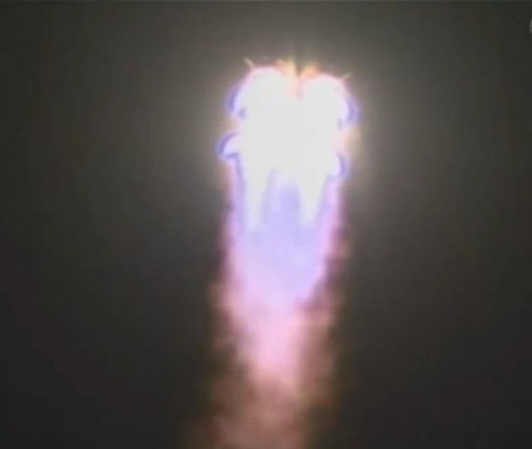 The blast of a Russian Soyuz rocket lights up the night.