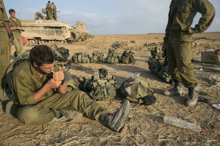 Image: An Israeli soldier smokes a cigarette after crossing back into Israel from Gaza