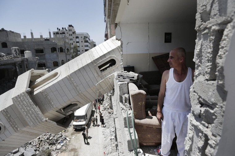Image: Palestinian Ismail Radwan, 45, inspects the damage to his family apartment