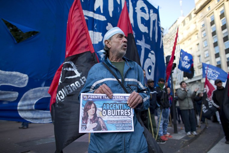 Image: An activist holds a newspaper with a headline that reads in Spanish \"Argentina or vultures,\"