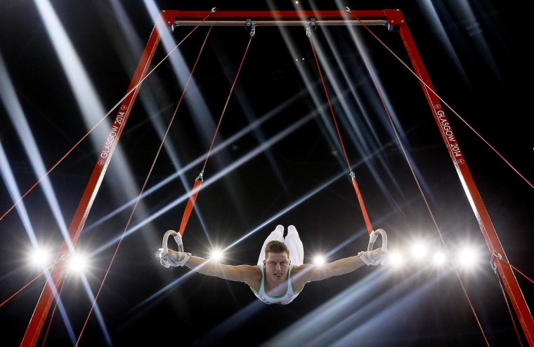 Image: Lights flare as Harry Owen of Wales performs on the rings during the Men's All-Around gymnastics competition