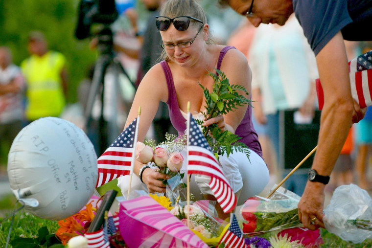 Image: Gail Krull of West St. Paul, Minn. a niece of Mendota Heights, Minn. Police Officer Scott Patrick, cries as she lays a bouquet of roses on a makeshift memorial