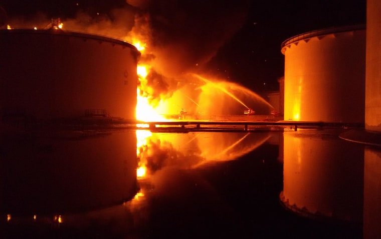 Image: Libyan firefighters dousing a huge blaze at an oil tank