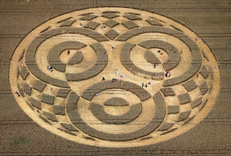 Image: People walk through crop circles shaped into a cornfield