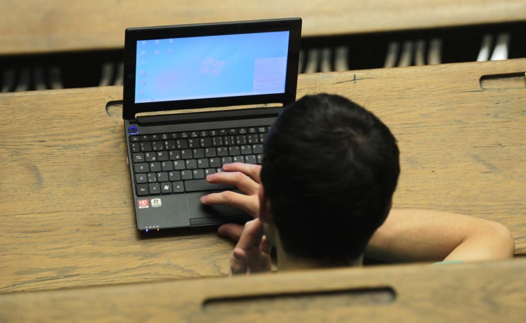Image: A students works with his computer attending a lecture in an auditorium