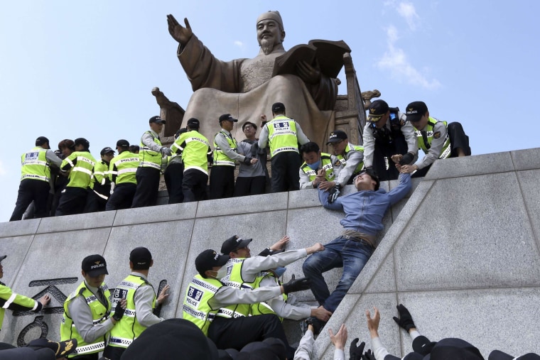 Image: Policemen detain university students on a statue of King Sejong the Great during a protest against South Korean President Park Geun-hye, in central Seoul