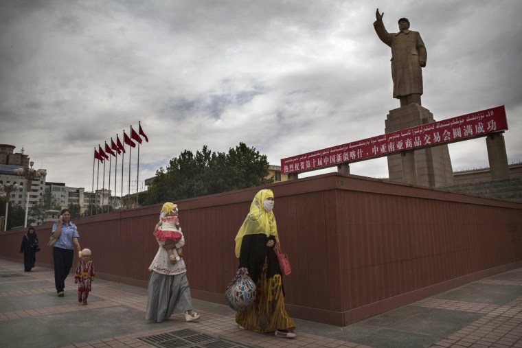 A veiled Muslim Uighur woman walks passed a statue of Mao Zedong on July 31, 2014 in Kashgar in China's restive Xinjiang Province.