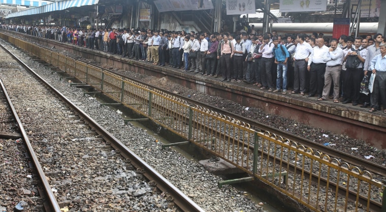 Image: Indian commuters wait on an over-crowded platform to board a local train at a suburb railway station in Mumbai.
