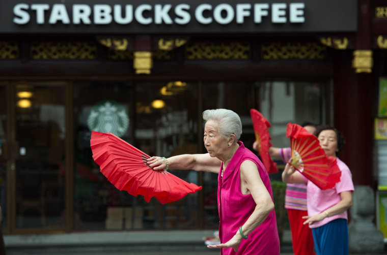 Image: Women do morning exercises in front of a Starbucks restaurant