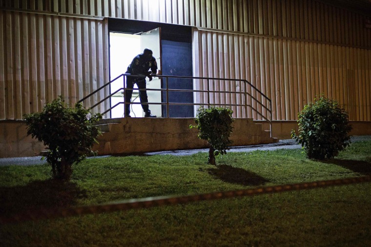 Image: A police officer stands at the door of a community recreation center during a curfew law in Baltimore