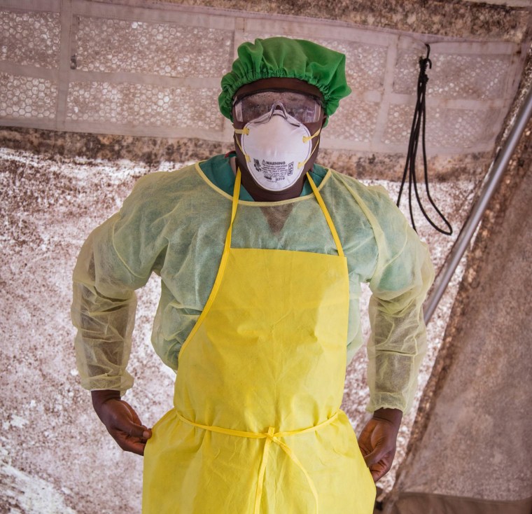 Image: A health worker prepares to examine patients for Ebola