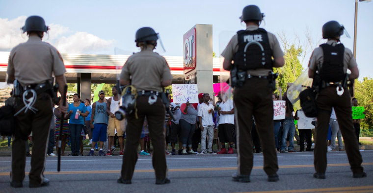 Image: Police officers watch as demonstrators protest the death of black teenager Michael Brown in Ferguson