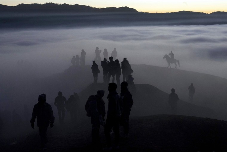 Image: Indonesian villagers  wait on the edge of the crater to catch offerings