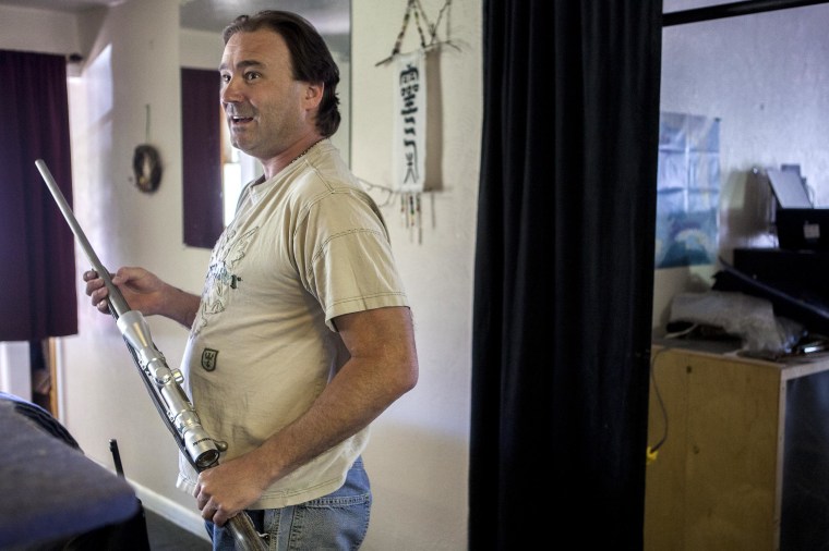 iMAGE: Bill Long handles one of the guns, a .300-caliber magnum rifle, he keeps at his home in Nucla, Colo.