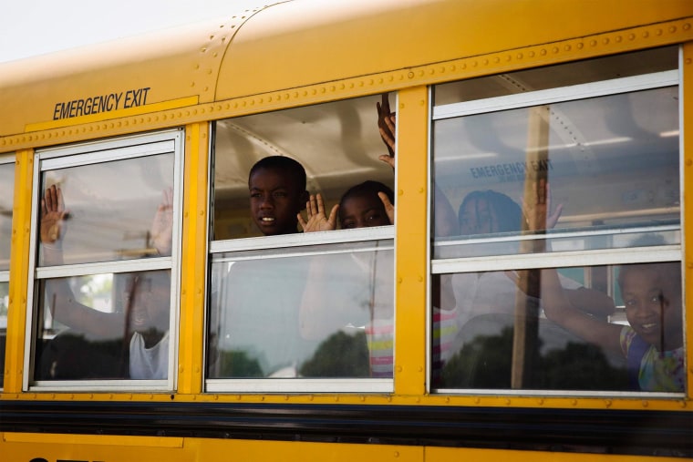 Image: Children on a school bus gesture and chant, \"Hands up, don't shoot\"