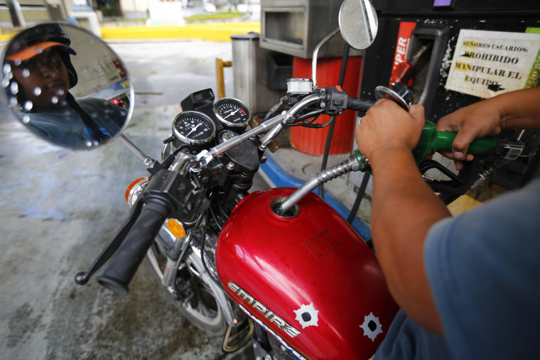 Image: A man pumps gasoline at a service station in Caracas