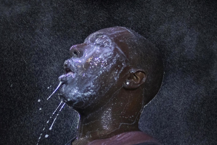 Image: A man is doused with milk and sprayed with mist after being hit by an eye irritant from security forces trying to disperse demonstrators protesting against the shooting of Brown in Ferguson