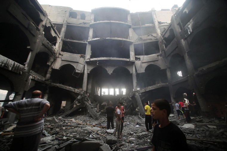Image: Palestinians inspect the rubble of a shopping center