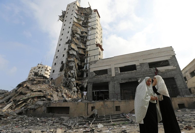 Image: Palestinian women stand next to the remains of one of Gaza's tallest apartment towers, which witnesses said was hit by an Israeli air strike that destroyed much of it, in Gaza City