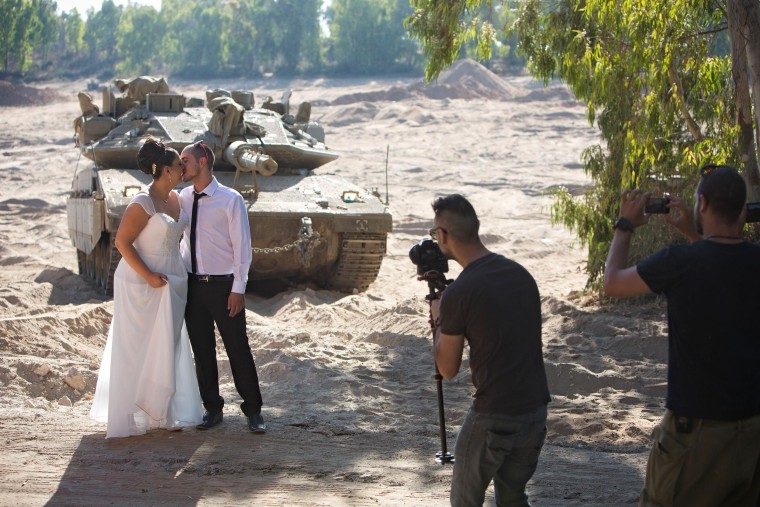 Image: Israeli couple, Noga and Moshiko Siho, have their wedding photo taken in an army staging area on the Israeli Gaza border, near Kibbutz Yad Mordechai, Israel