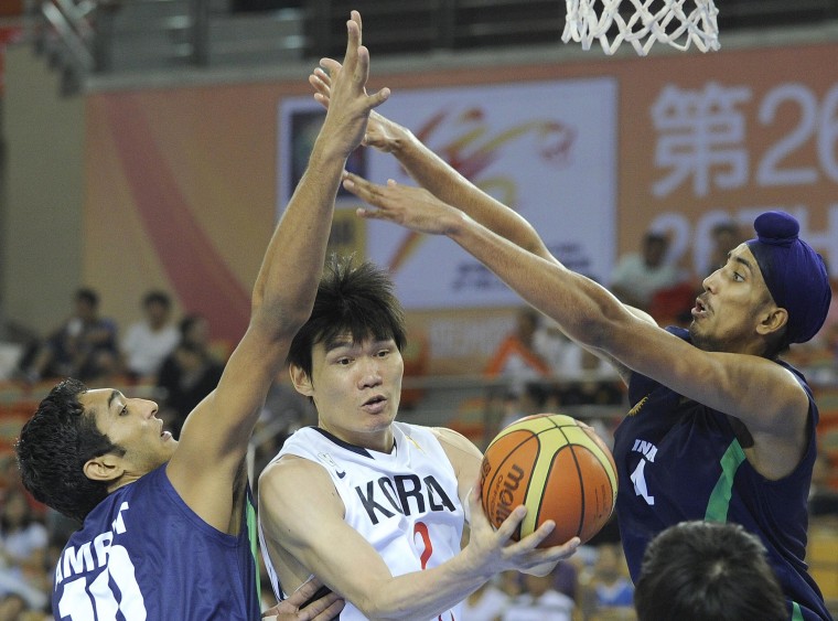 Image: Kim Joo Sung of South Korea, center, tries to pass the ball as Amjyot Singh, right, and Amritpal Singh of India defend during their preliminary round match between South Korea and India at the 26th Asian Basketball Championships in Wuhan in China