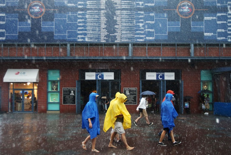 Image: Tennis fans walk barefoot as play is suspended during the 2014 U.S. Open tennis tournament.