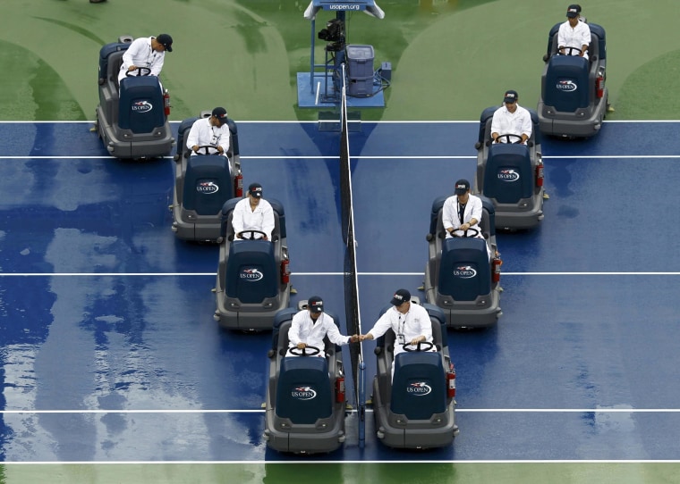 Image: Workers dry the court after a suspension of play due to rain at the 2014 U.S. Open tennis tournament in New York