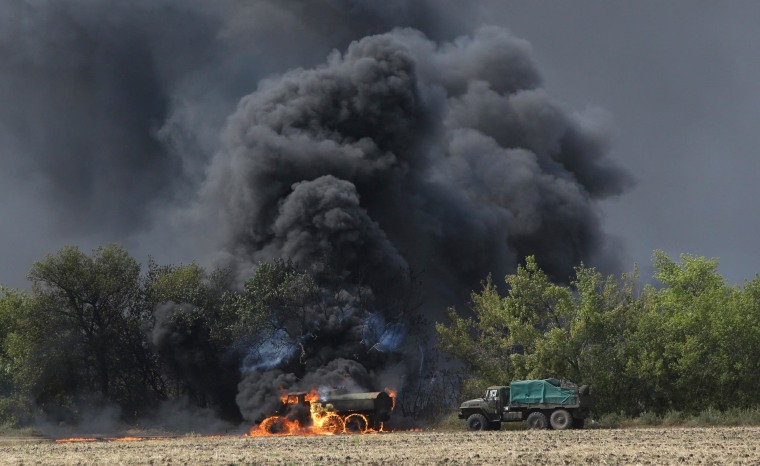 Image: An unmarked military vehicle burns on a country road in the village of Berezove, eastern Ukraine