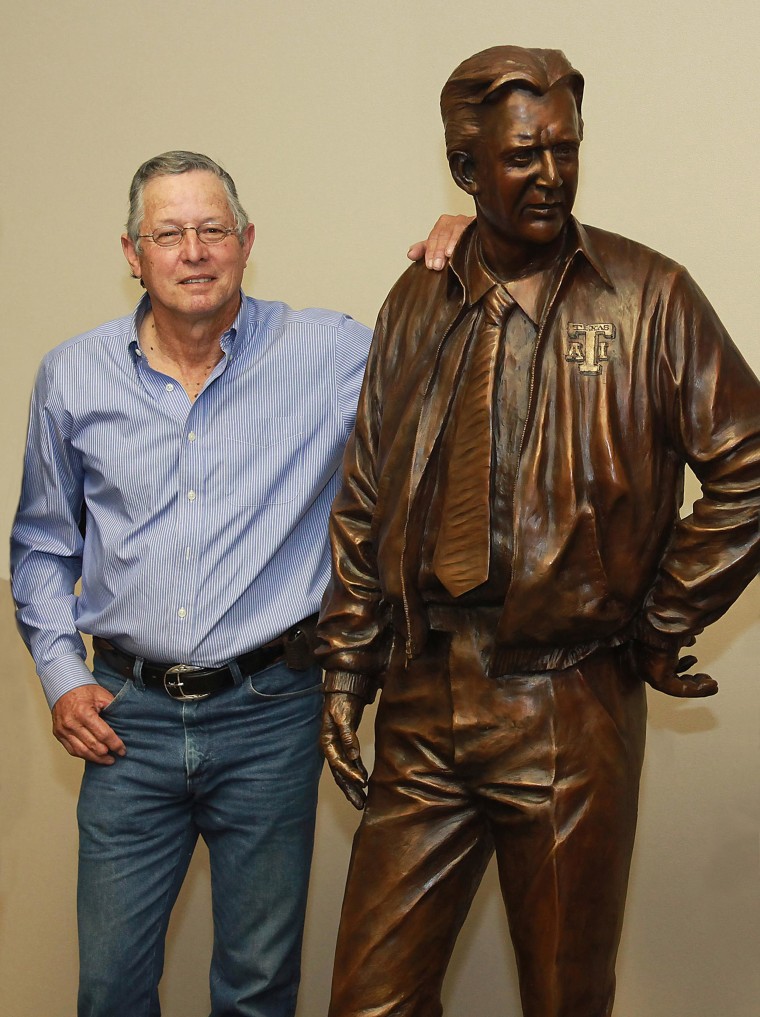 Sculptor Armando Hinojosa poses next to his life-size sculptor of legendary Texas college football coach Gil Steinke.