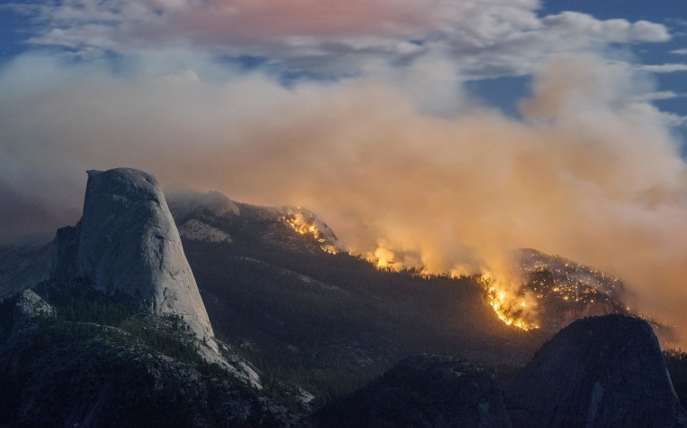 In this Sunday, Sept. 7, 2014, photo provided by Michael Frye, a wildfire burns next to Half Dome in Yosemite National Park, Calif.  As of Monday, the fire has burned through about four square miles.