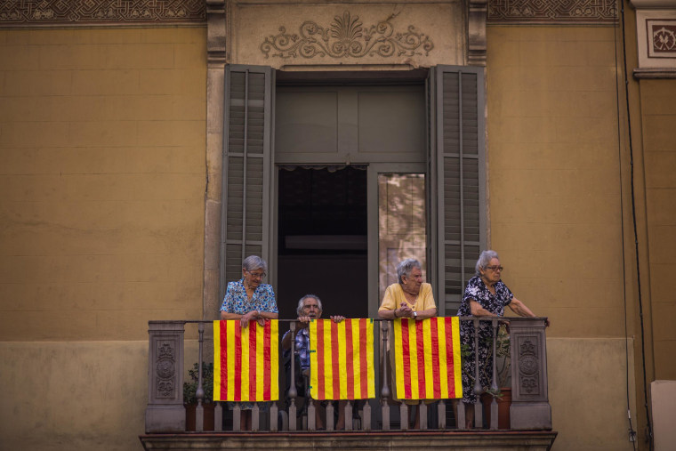 Image: People stand on a balcony decorated with Catalonia flags in Barcelona