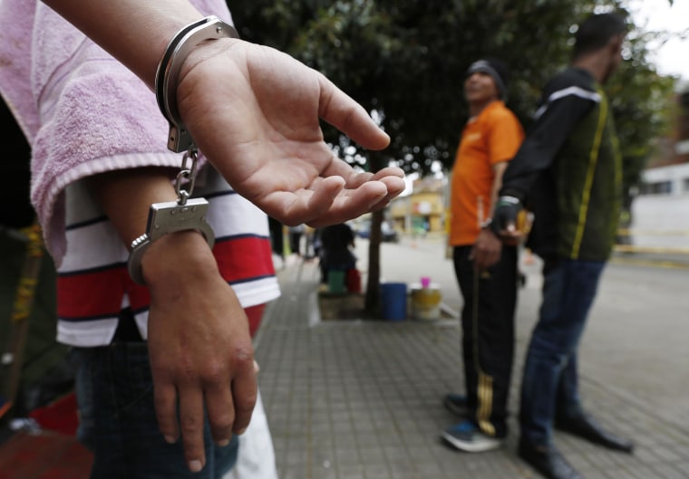Image: Detainees, handcuffed to each other, stand at a public park in Bogota, Colombia