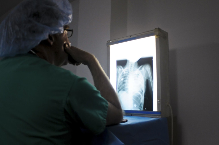Image: A doctor from an international cardiac mission examines the x-ray of a patient's heart in the Degand Clinic in Port-au-Prince