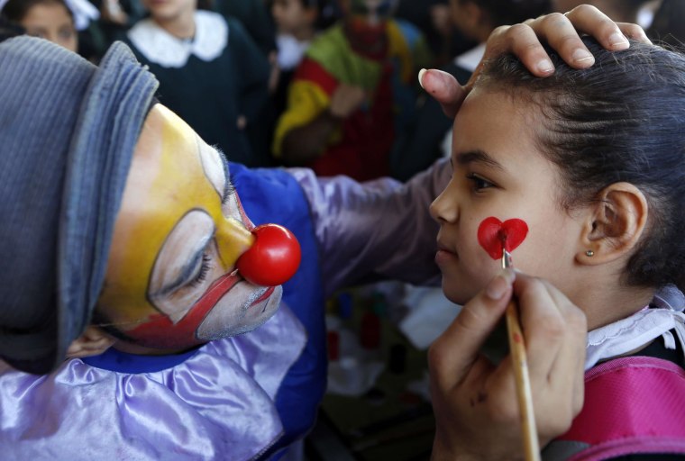 Image: A Palestinian clown paints the face of a student